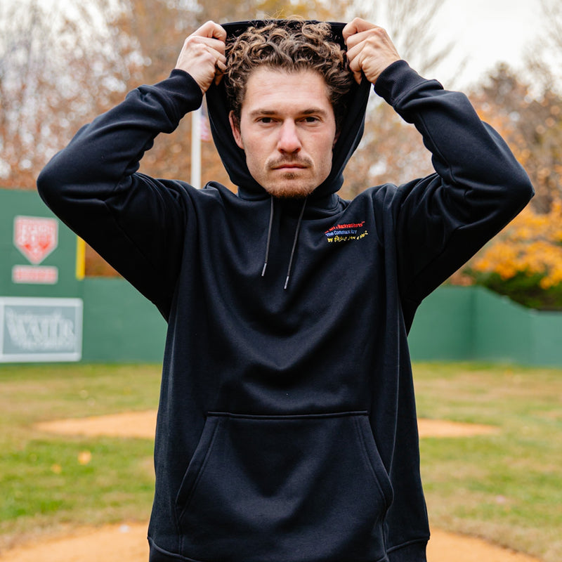 Man wearing a black hoodie with a logo on a sports field