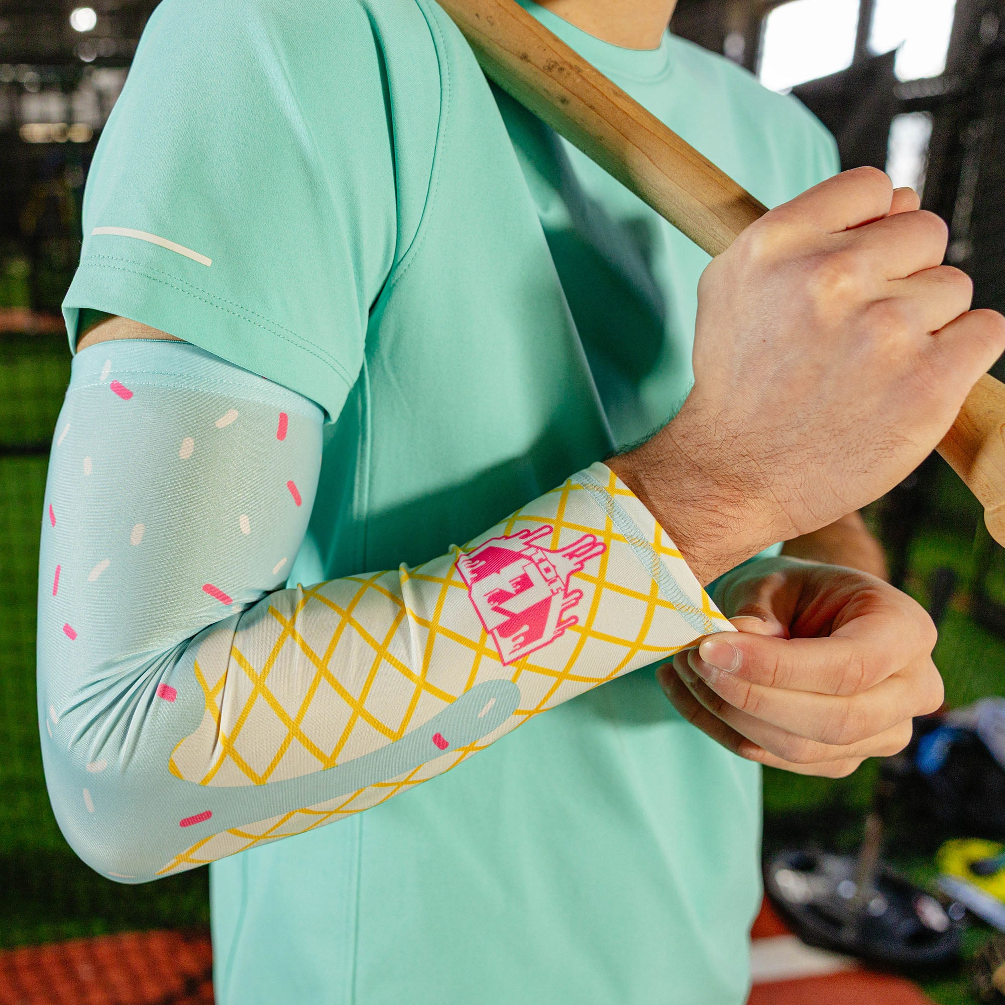 Close-up of the cotton candy ice cream arm sleeve on a player's arm showing the light blue sprinkle print waffle cone design and pink BL101 logo near the wrist