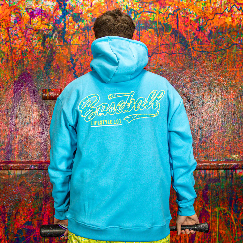 Person wearing a blue hoodie with 'Baseball Lifestyle 101' text on the back against a colorful, textured wall.