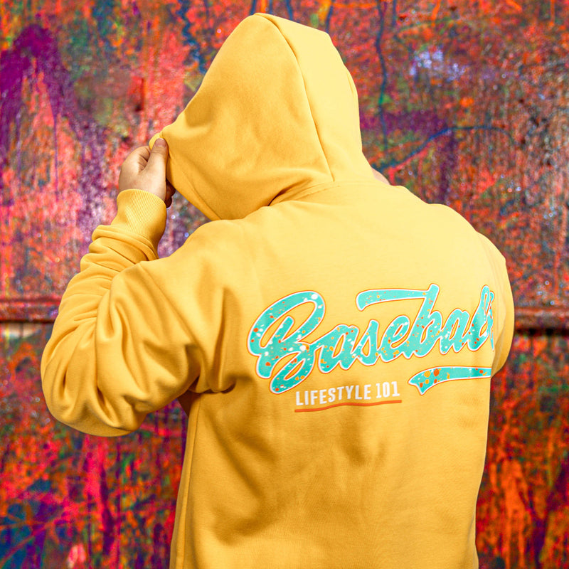 Person wearing a orange hoodie with 'Baseball Lifestyle 101' text on the back against a colorful abstract background.