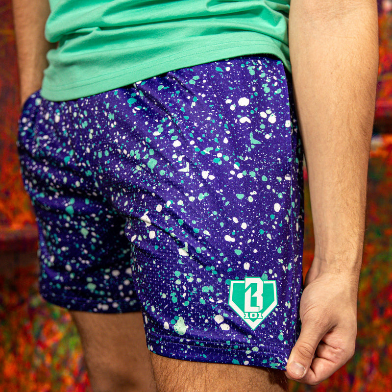 Person wearing purple shorts with a pattern and a BL101 logo, standing against a colorful background.