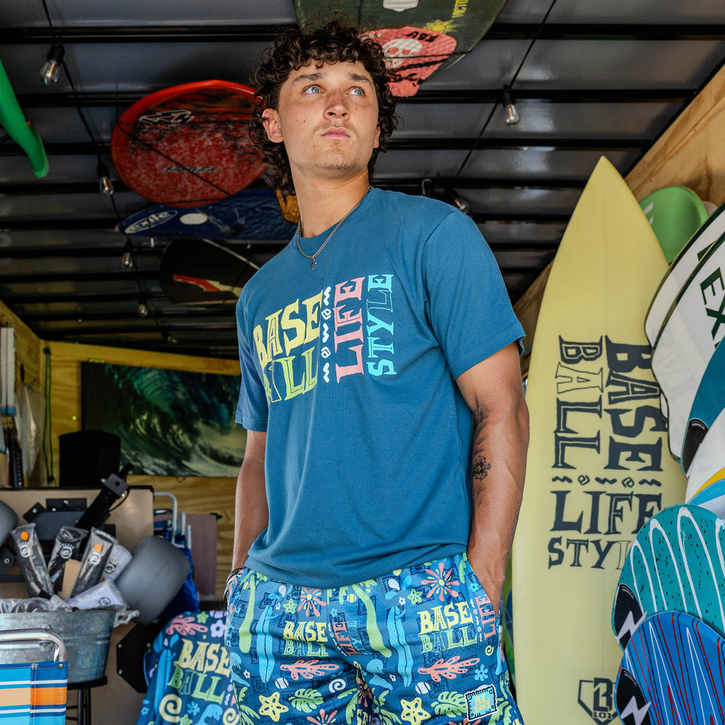 Adult model wearing blue graphic tee with "Surfside Slugger" design