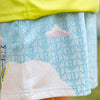 Close-up of a child's outfit with a blue cloud patterned shorts and yellow shirt.