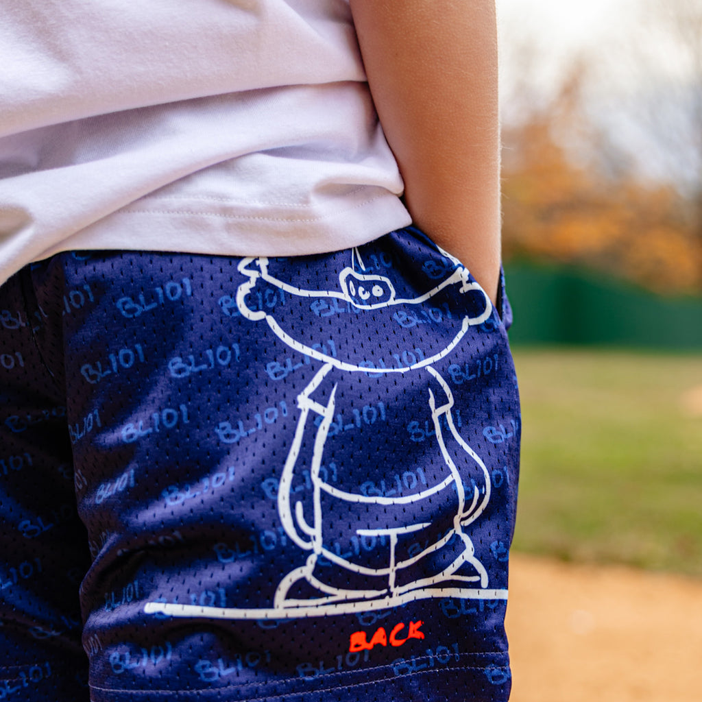 Person wearing blue shorts with a white Pablo Sanchez graphic design outdoors
