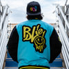 Person wearing a blue, yellow and black jacket with yellow BL101 logo, standing on a staircase.