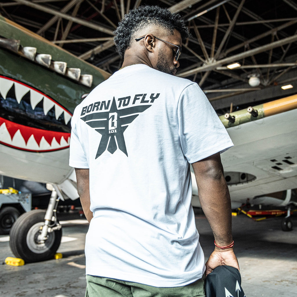 White t-shirt with black “BORN TO FLY” lettering, black star, and white BL101 logo centered inside the star on person