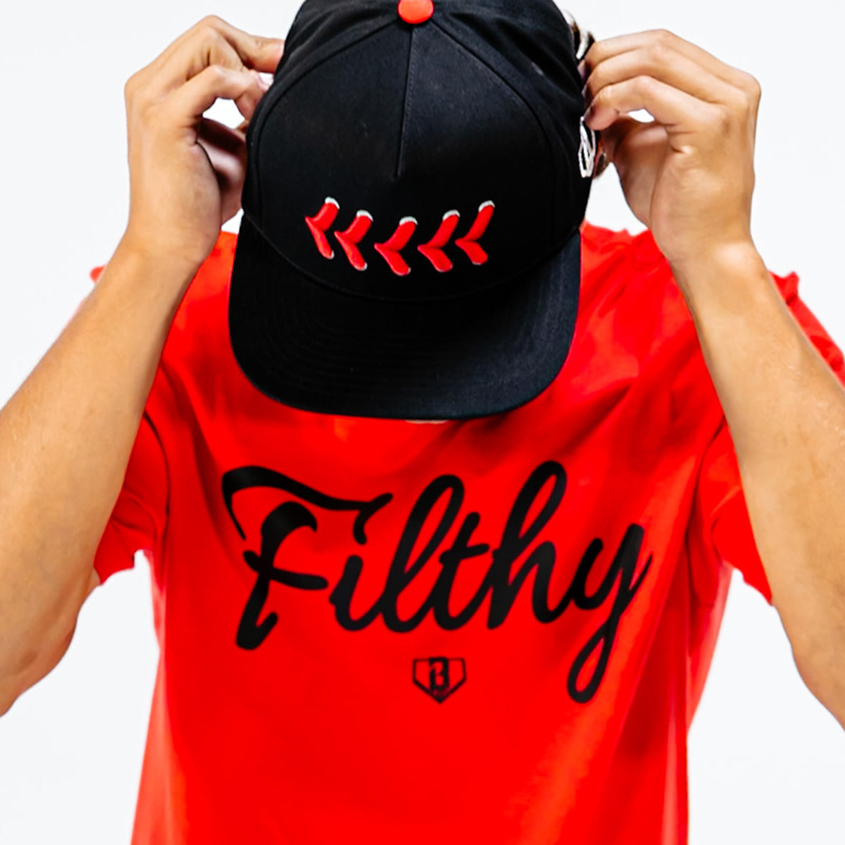 Person wearing a black cap with red stitching and a red shirt with 'Filthy' text.