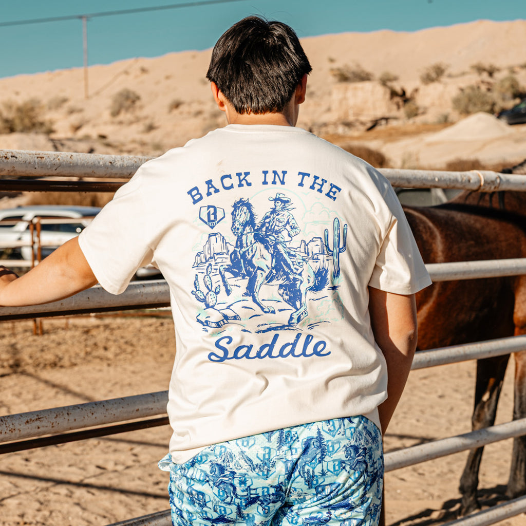 Adult model wearing white graphic tee with “Saddle Up N Swing Relaxed” design