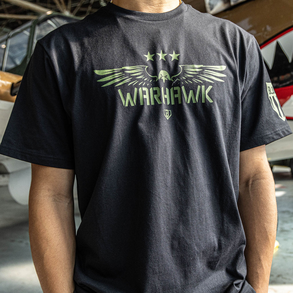 Close up of Black t-shirt featuring an army green eagle graphic with green “WARHAWK” lettering and a green Armor BL101 logo