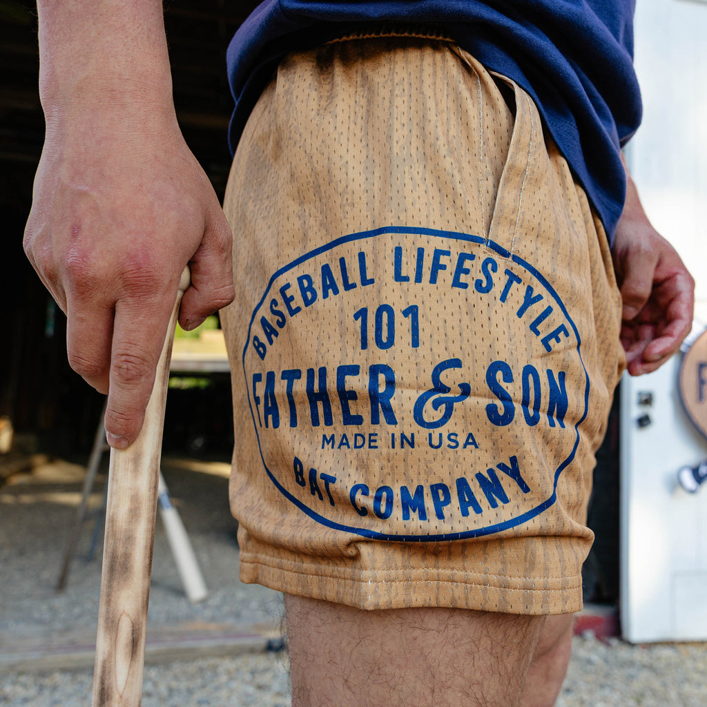 Side detail shot of the brown BL101 Bat Co Shorts highlighting the large Father & Son Bat Company oval stamp graphic on the left leg.