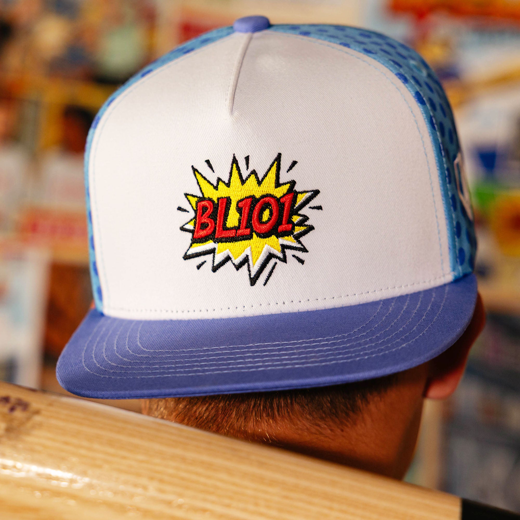 Adult model wearing blue hat with "BL101 Comic" design