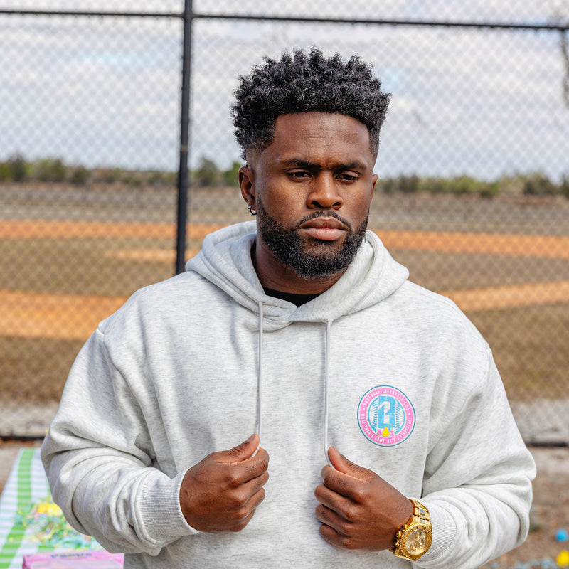 Man wearing a gray hoodie with a colorful BL101 logo on a sports field