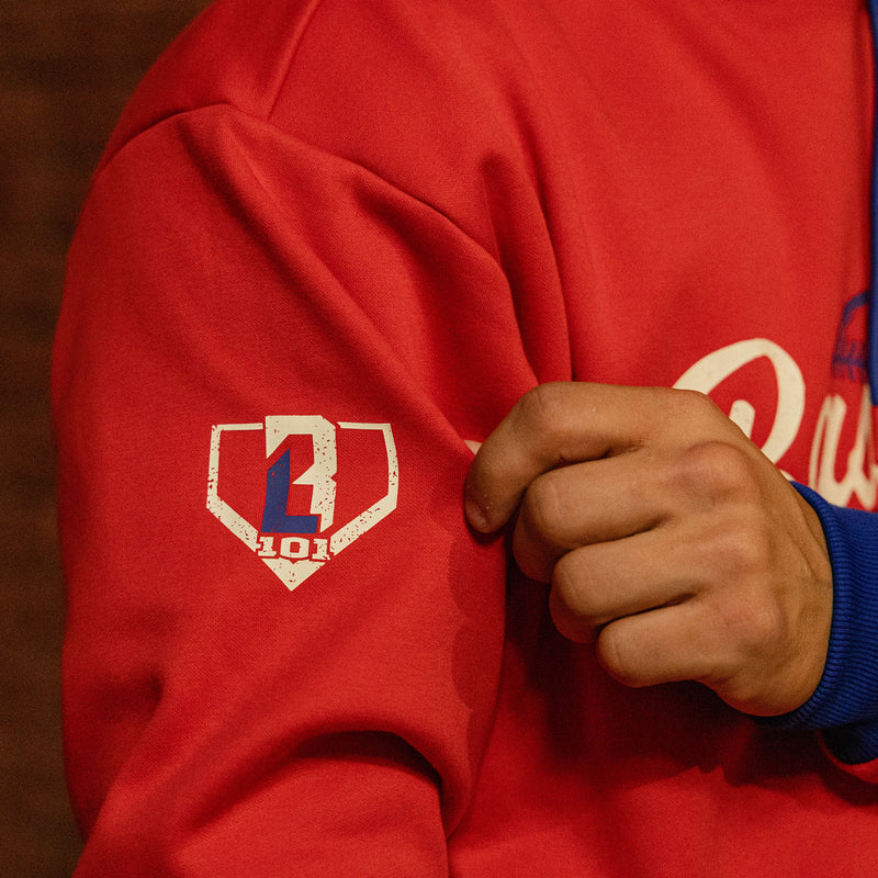 Close up of red Baseball Lifestyle hoodie sleeve showing BL101 home plate logo graphic and royal blue cuff