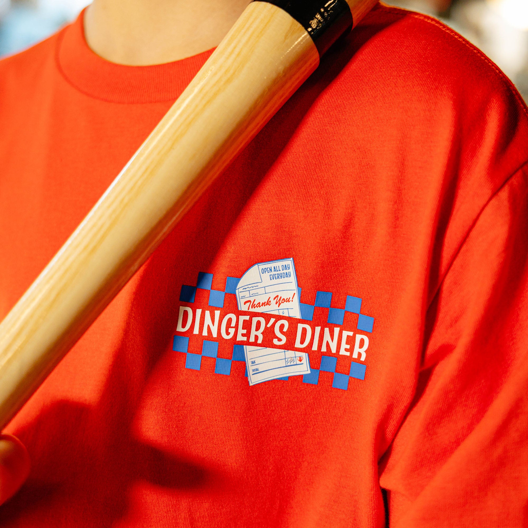 Close up of red t-shirt with a 'Dinger's Diner' logo on the front.