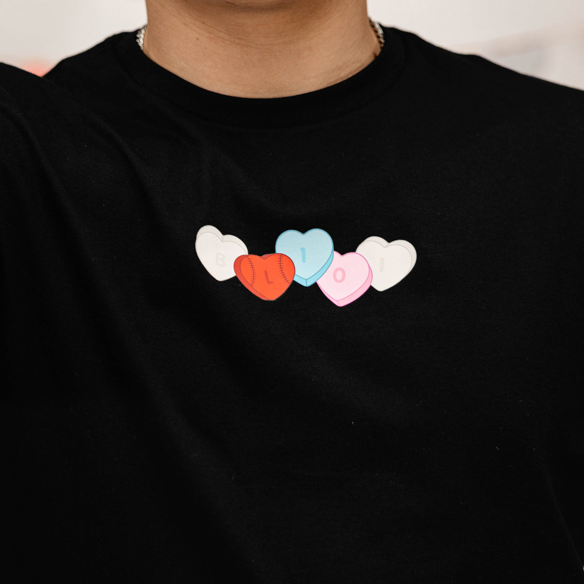 Black t-shirt with colorful heart-shaped letters on a plain background