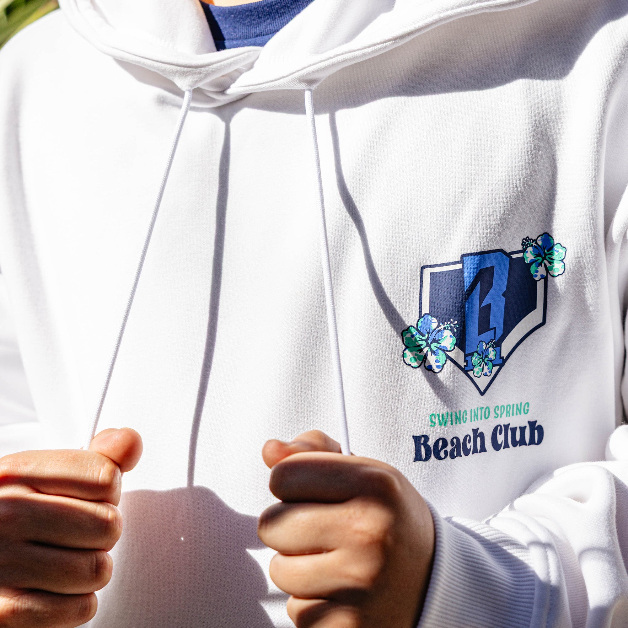 White hoodie with floral BL101 logo and 'Swing into Spring Beach Club' text