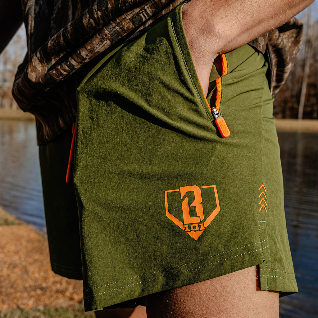 Green shorts with an orange BL101 logo worn by a person outdoors.