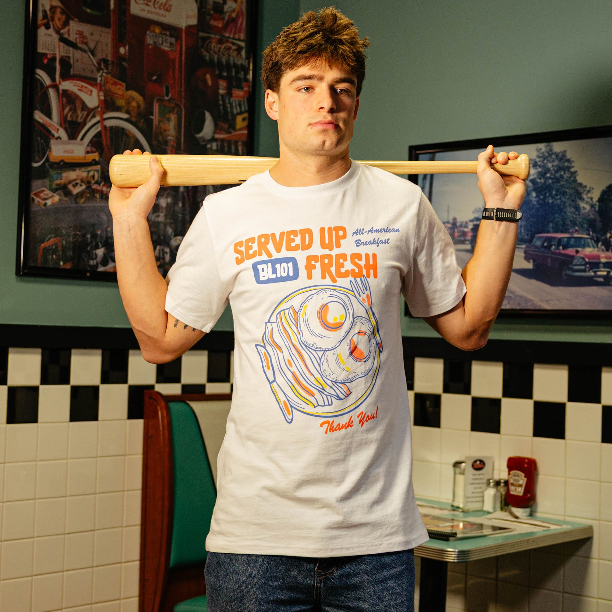 Person wearing a white t-shirt with a bacon and egg graphic and 'Served Up BL101 Fresh' text 