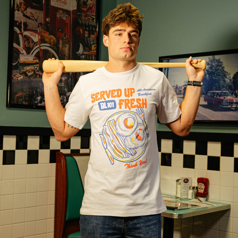 Person wearing a white t-shirt with a bacon and egg graphic and 'Served Up BL101 Fresh' text 