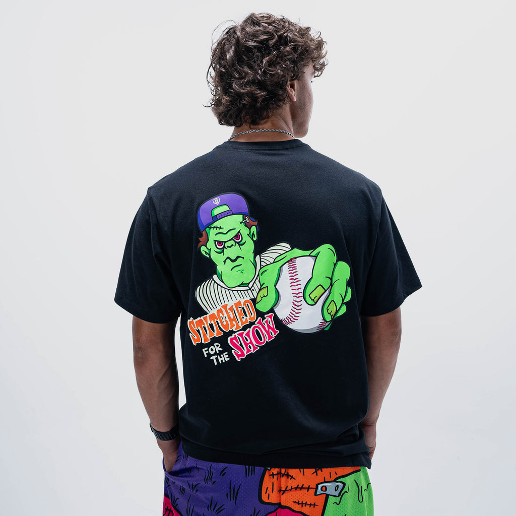 Adult model wearing black graphic tee with "Stitched For The Show" design
