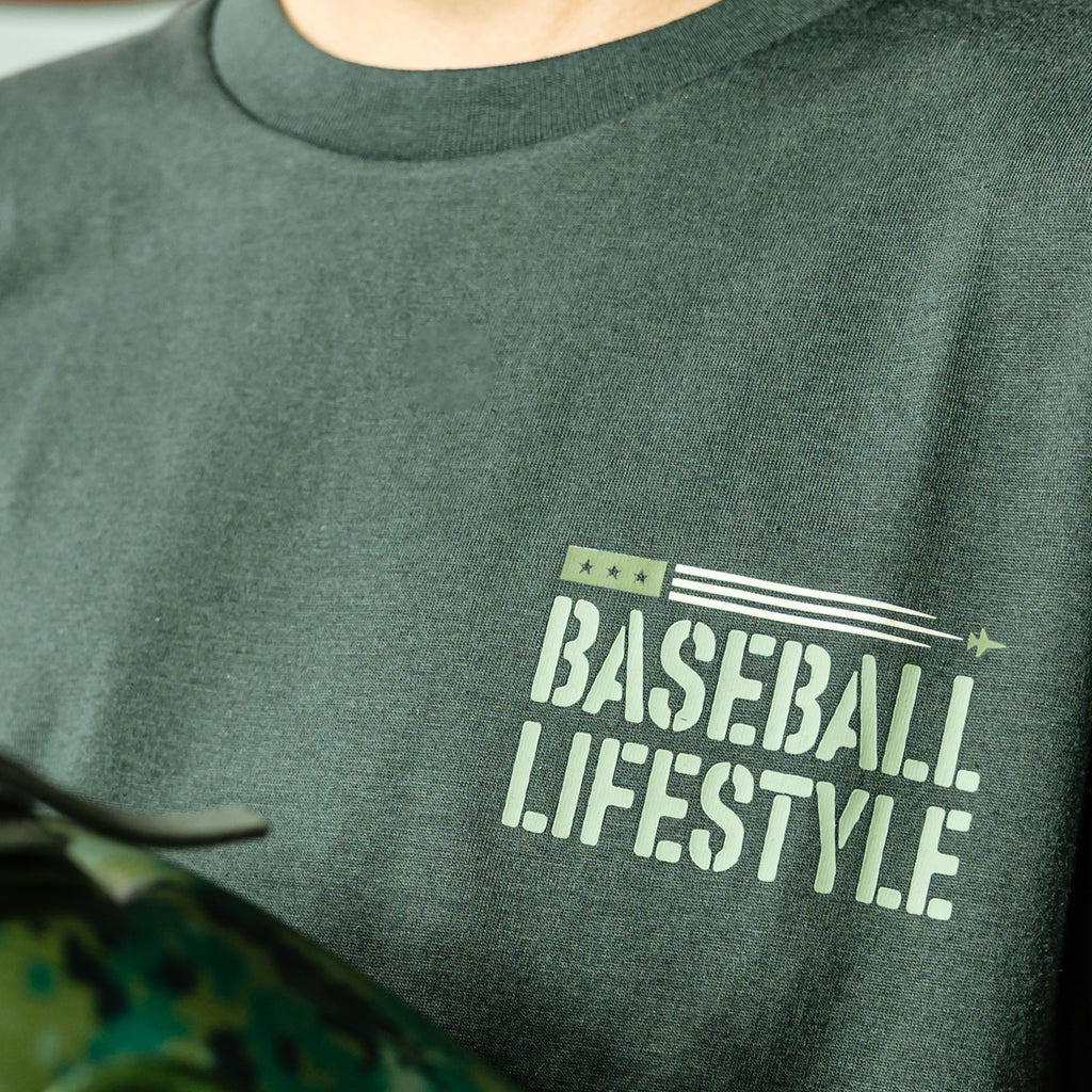 close up of green t-shirt with 'Baseball Lifestyle' text on a person wearing it.