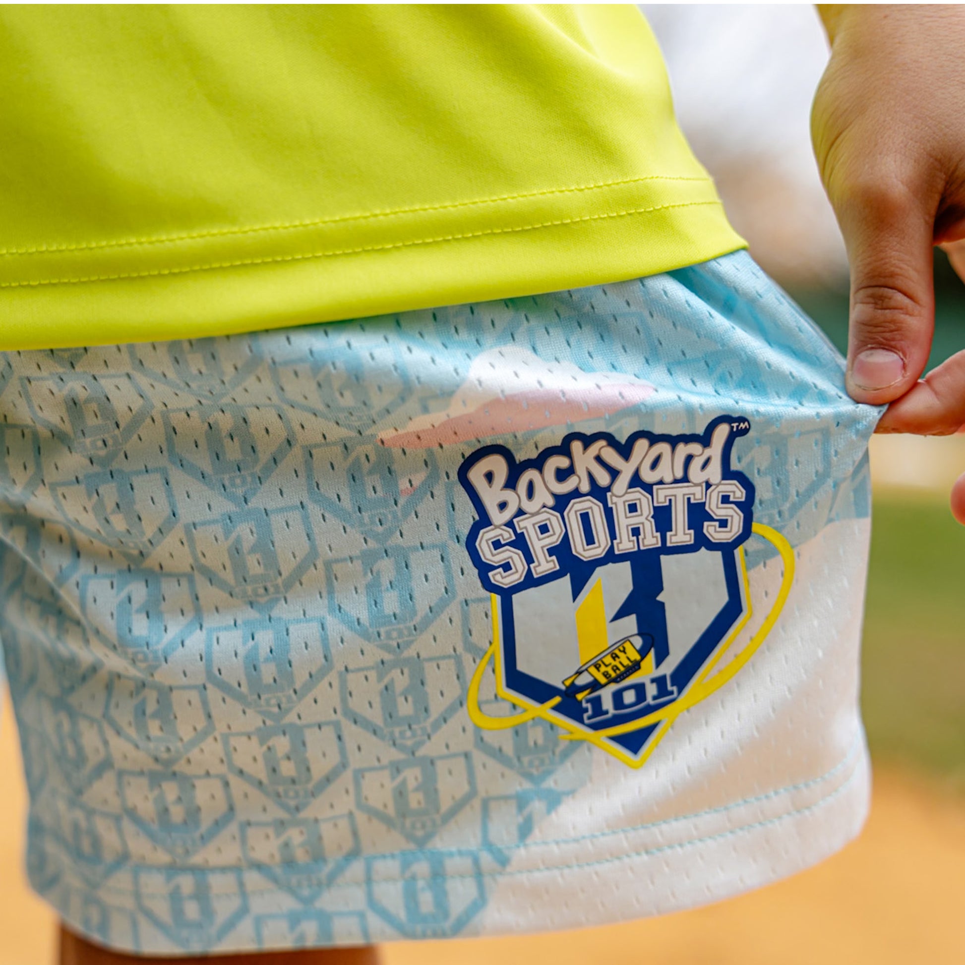 Blue shorts with a 'Backyard Sports' BL101 logo held by a person