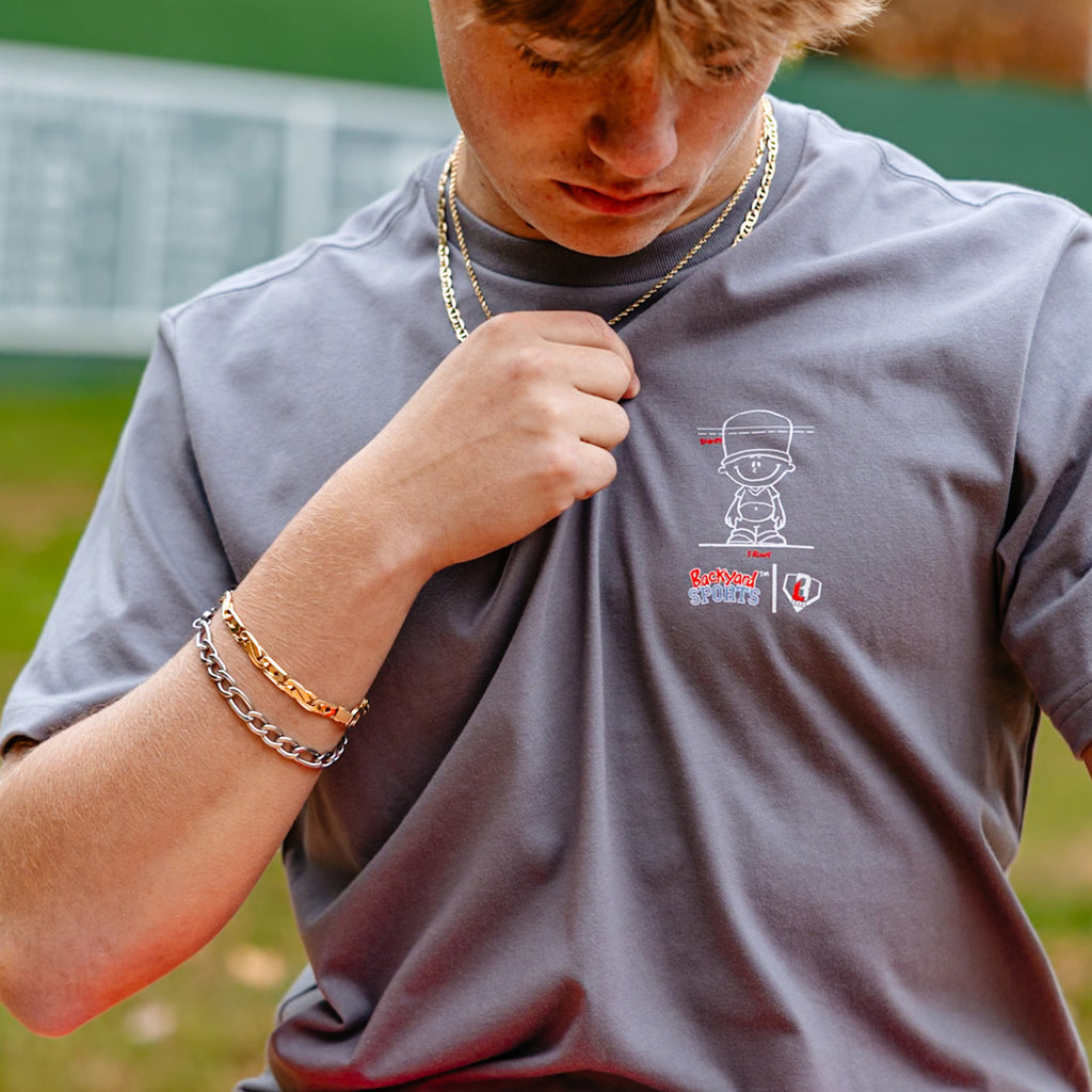 close up of person wearing a gray t-shirt with a Backyard Sports BL101 logo on a sports field