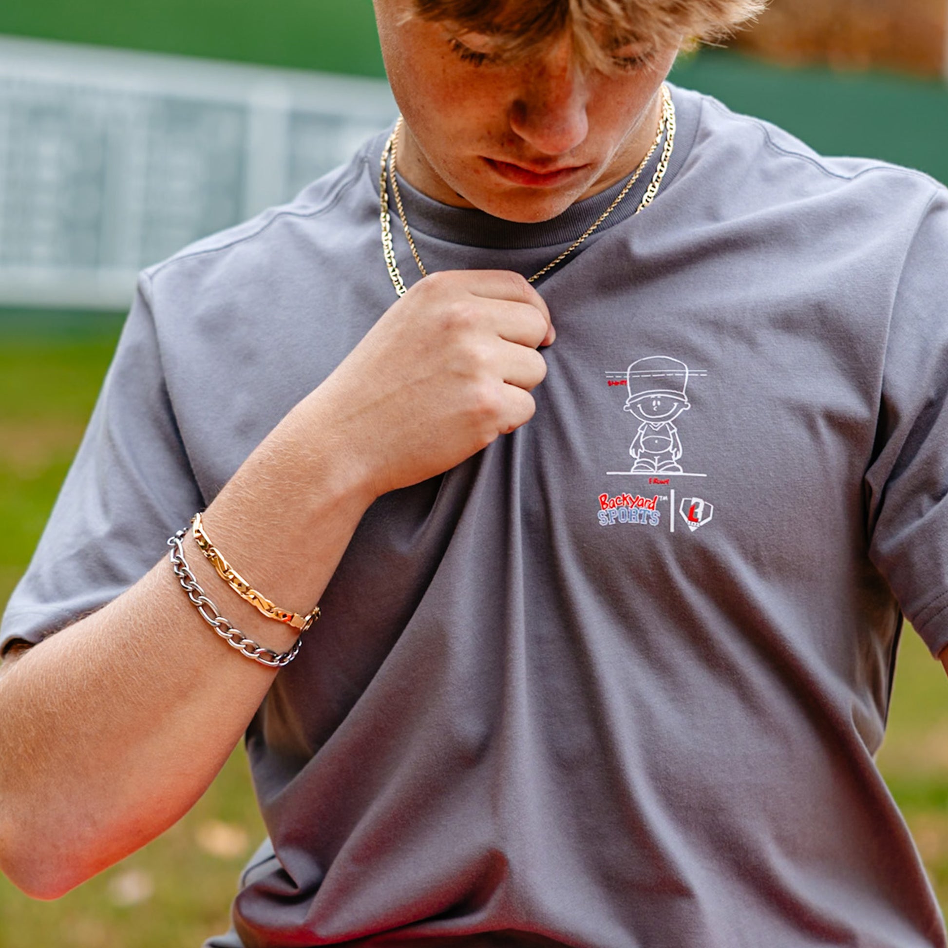 close up of person wearing a gray t-shirt with a Backyard Sports BL101 logo on a sports field