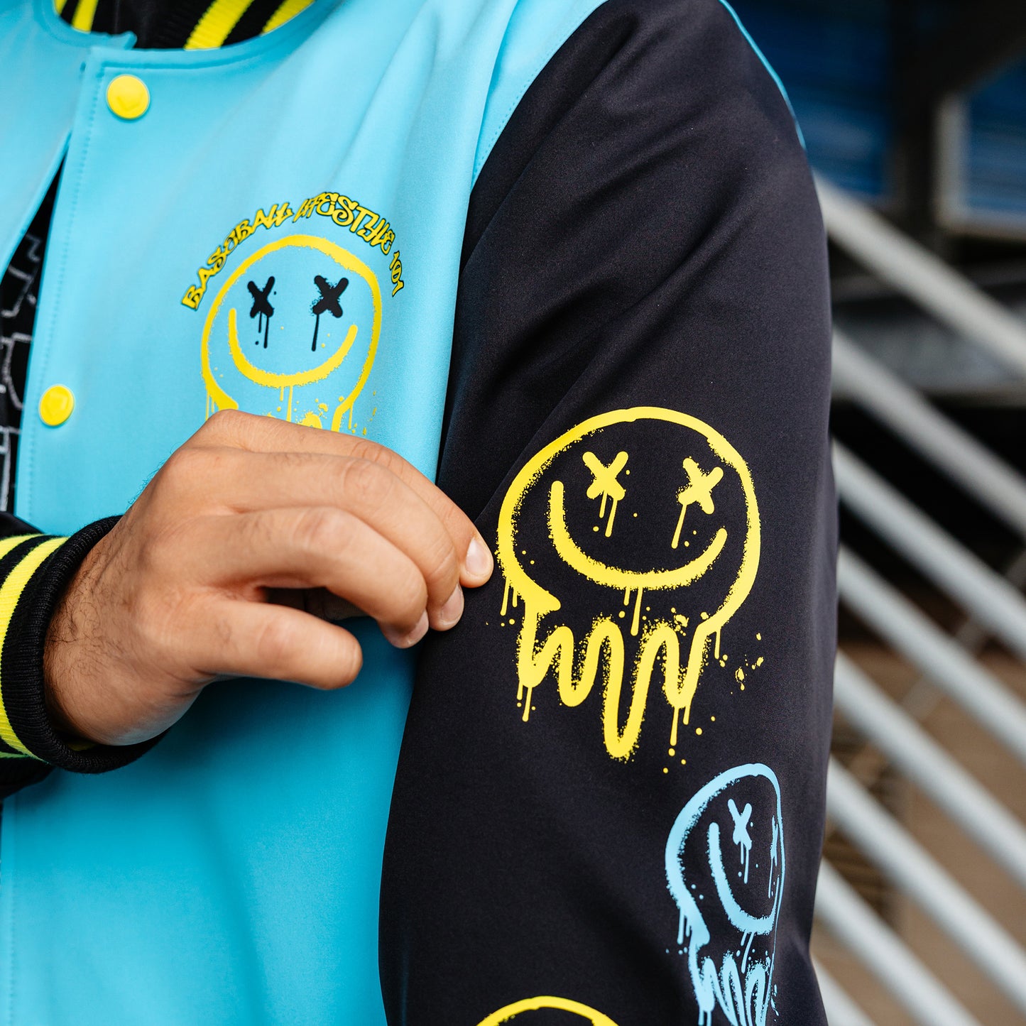 Person wearing a blue and black jacket with yellow smiley face designs.