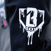 Black and grey hoodie with a white BL101 logo on the sleeve on a blurred background