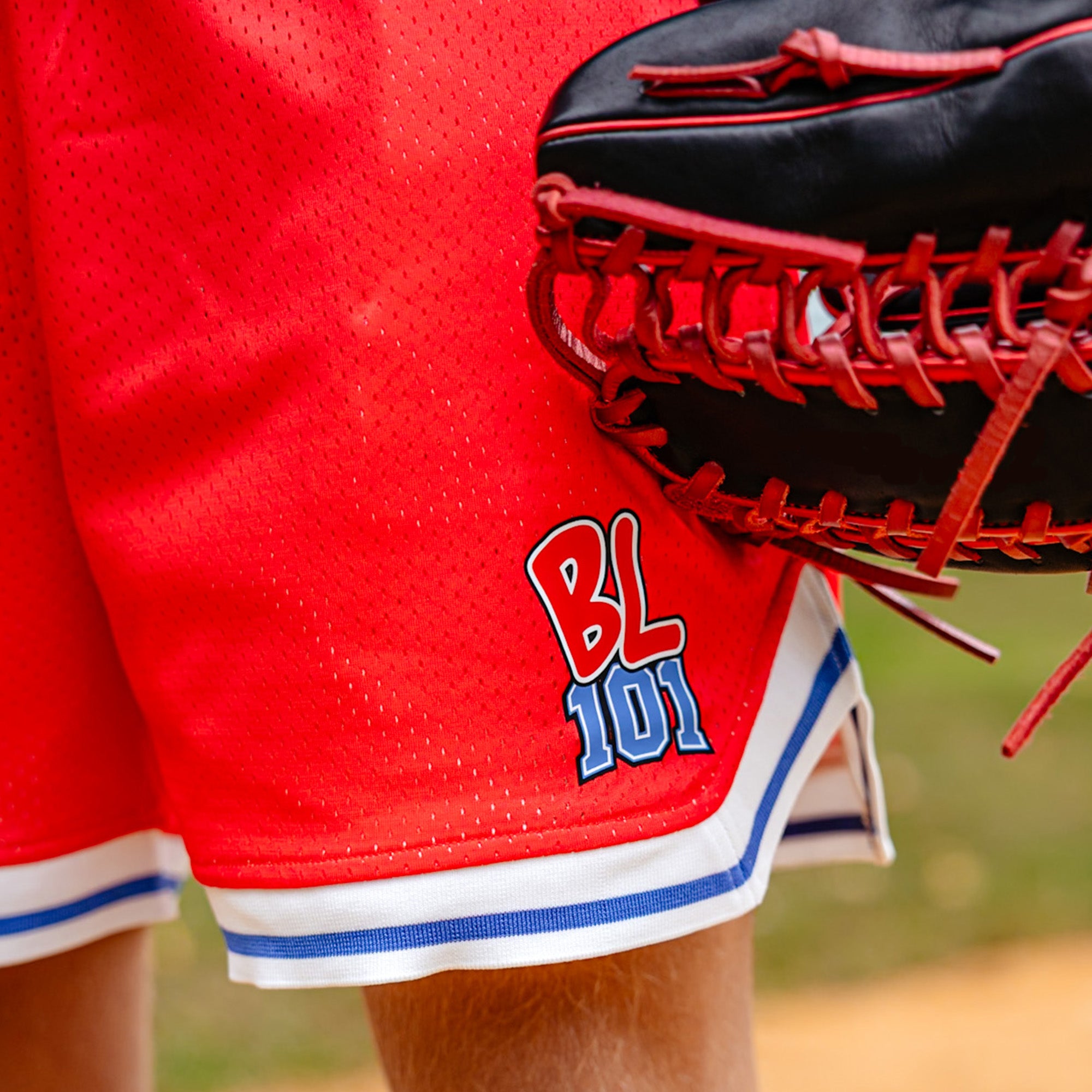 close up of person wearing a red shorts with 'BL101' logo and holding a baseball glove.
