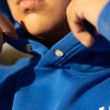Close-up of a person wearing a blue hoodie with a button being adjusted.