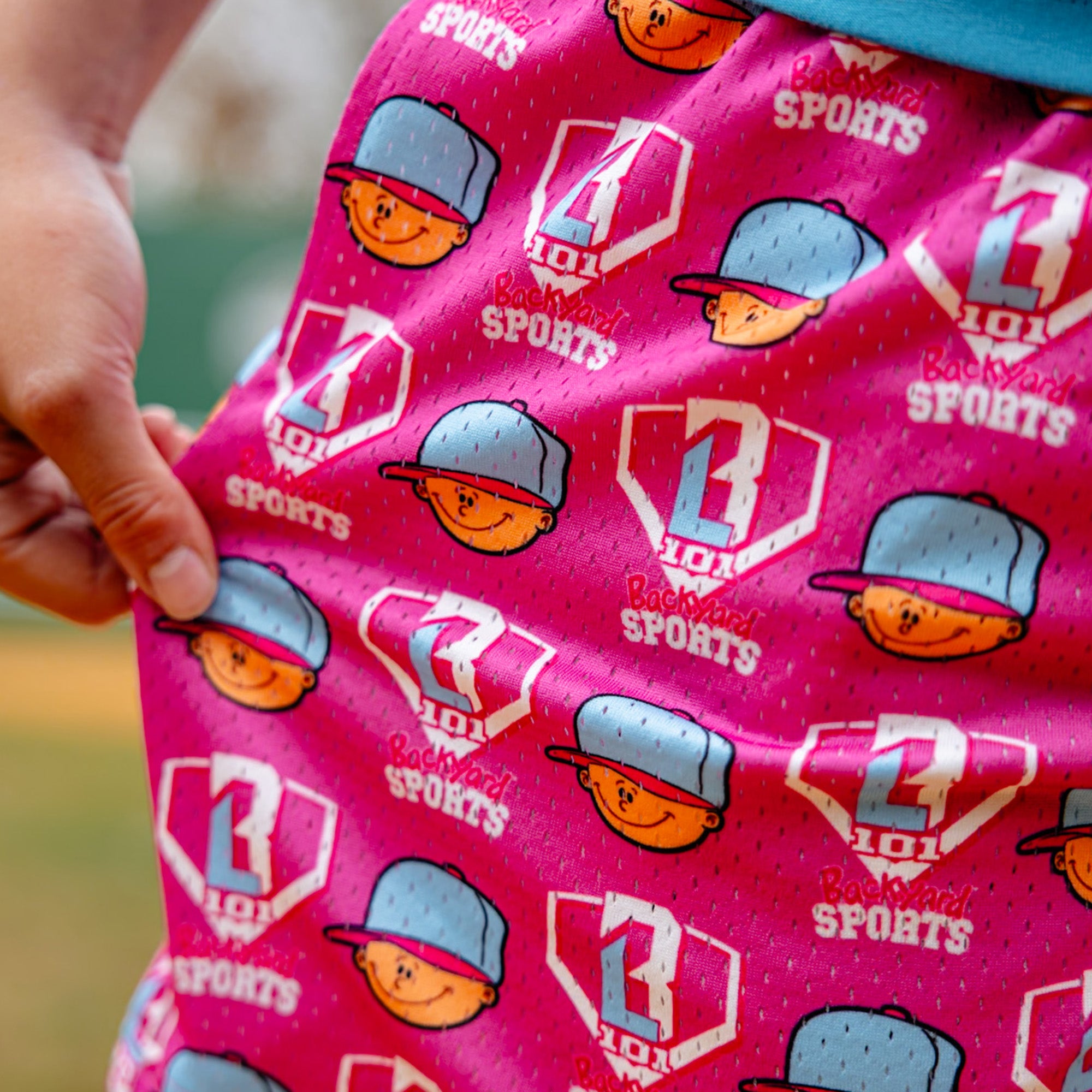 Pink fabric with Pablo Sanchez and 'BL101 Backyard Sports' logos, held by a hand.