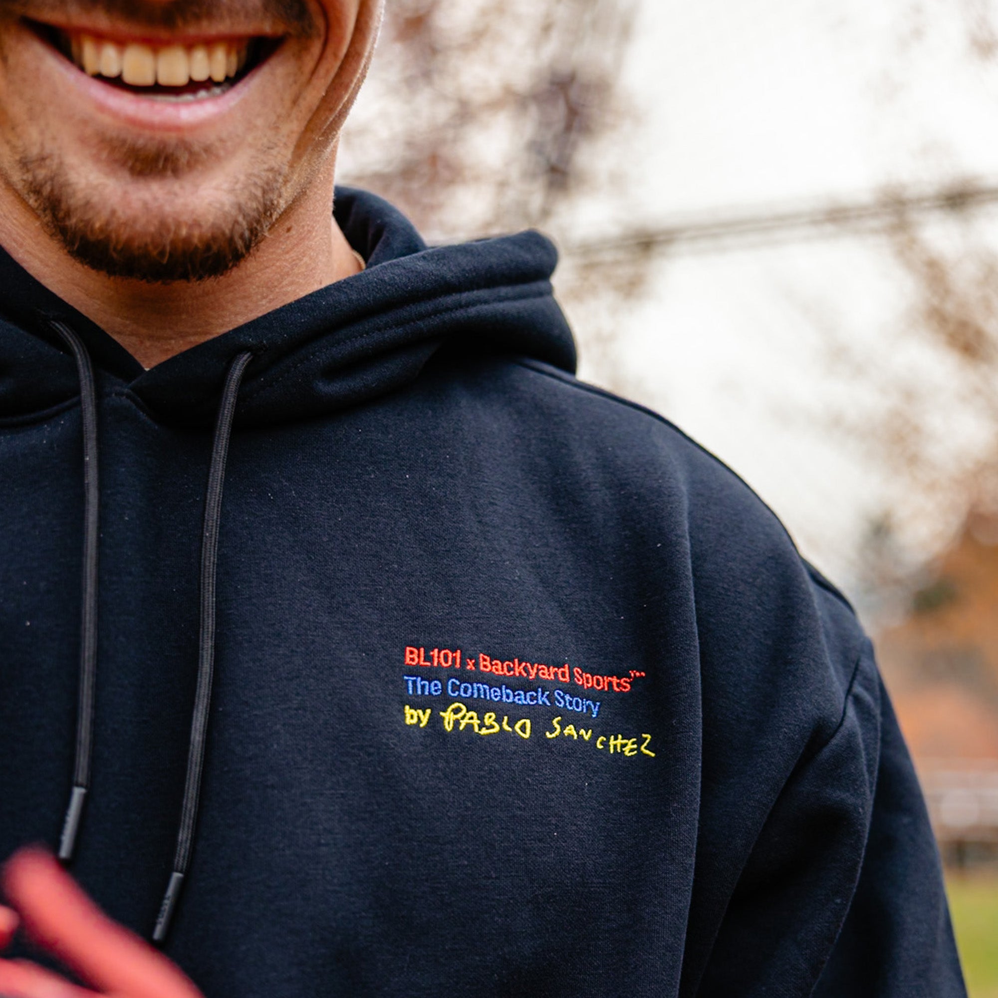 Close up of black hoodie with 'BL101 x Backyard sports The Comeback Story by Pablo Sanchez'