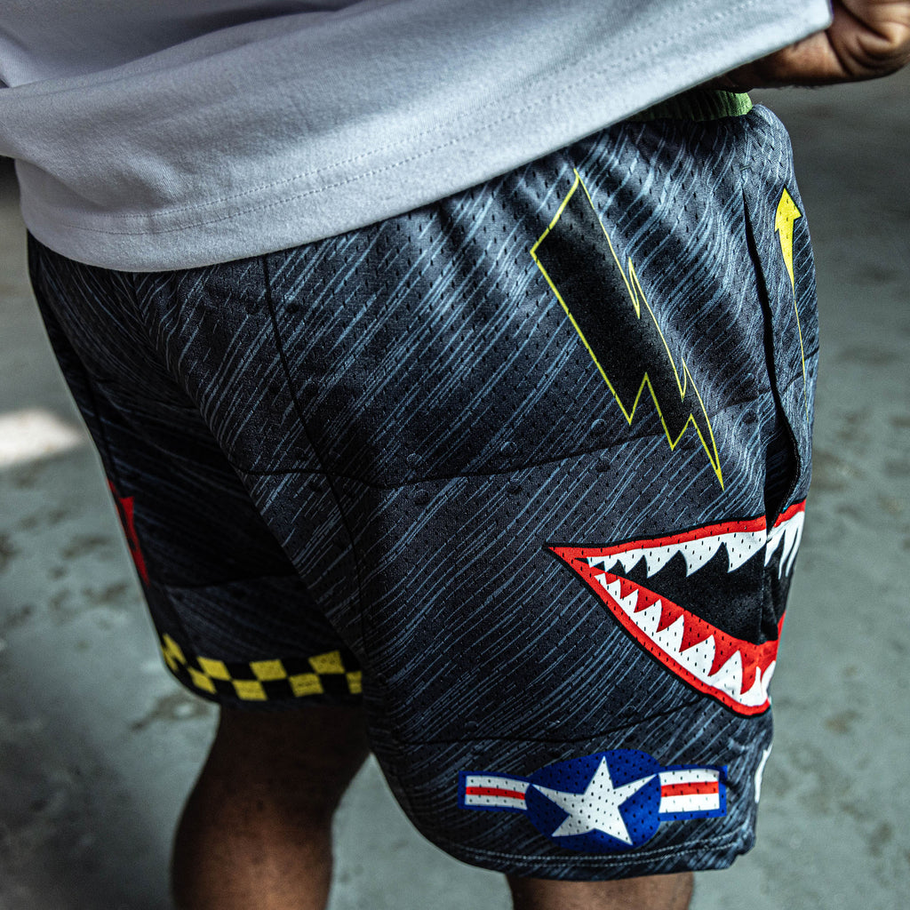 Close up of shorts with a shark mouth design and lightning bolt on a dark background