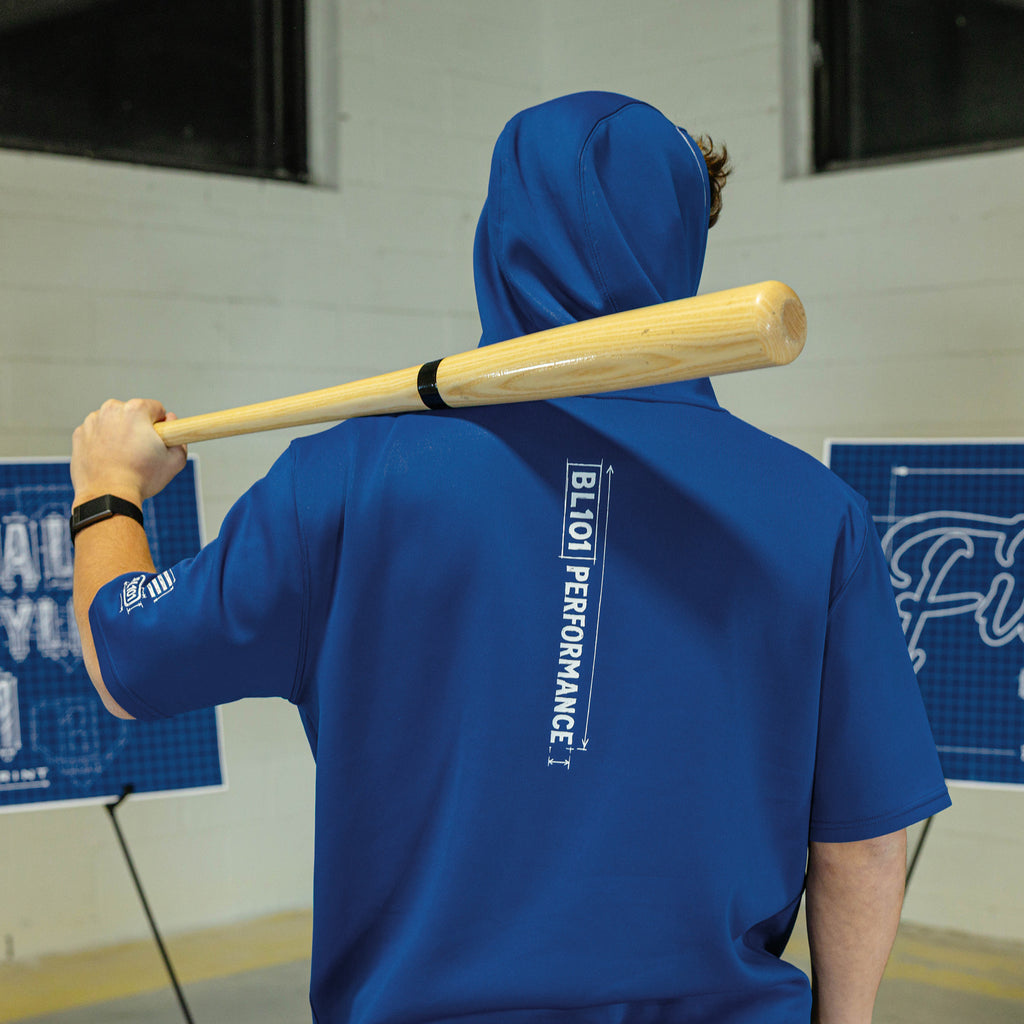 Person wearing a blue hoodie with 'BL101 Performance' text, holding a baseball bat.