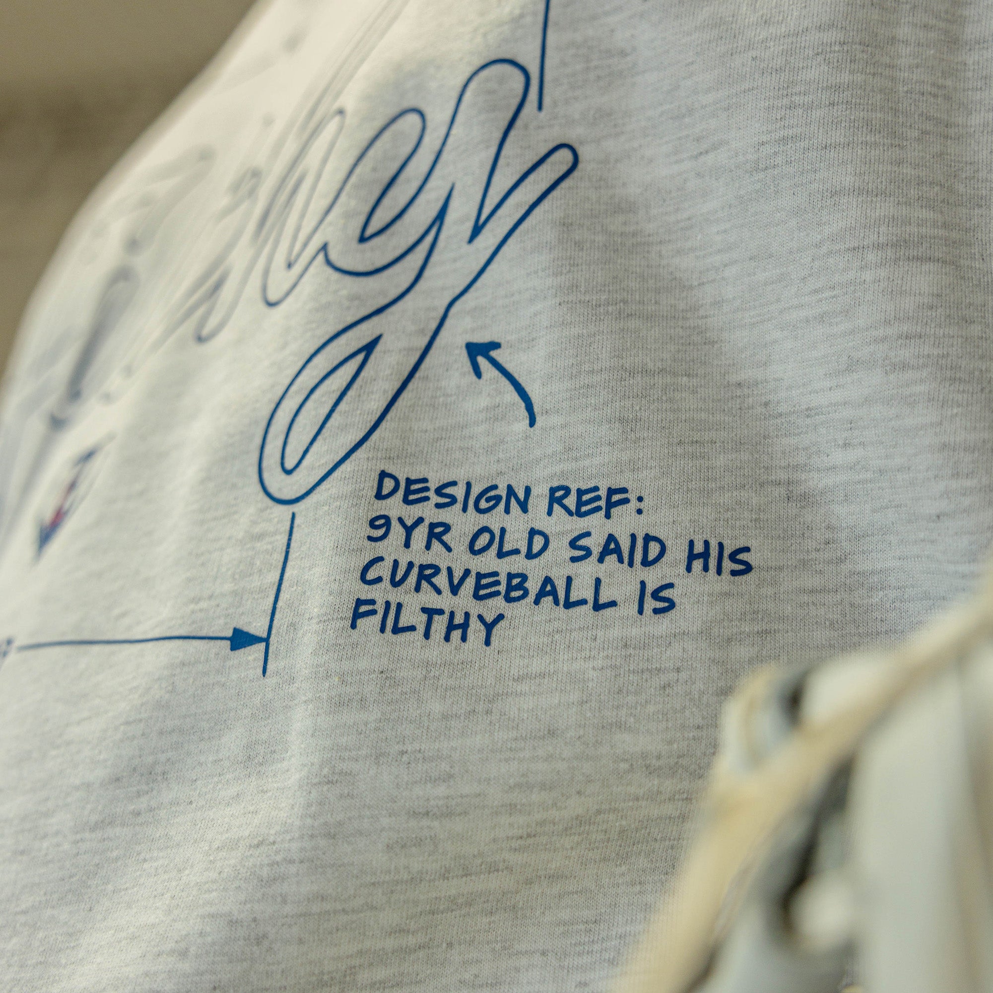 Gray sweatshirt with blue text and design elements on a blurred background