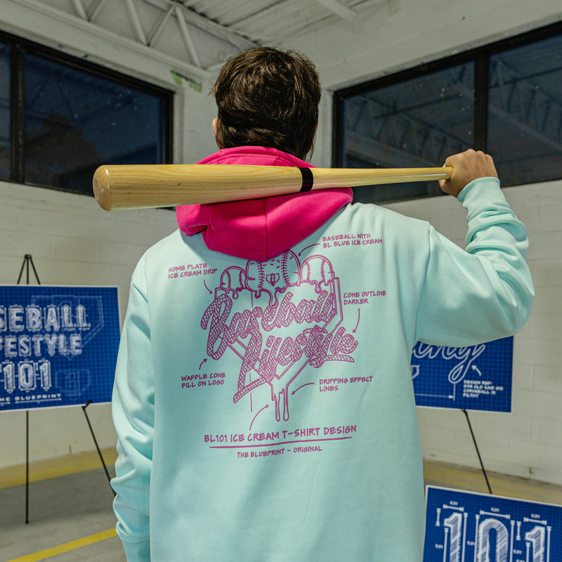 Person wearing a light blue hoodie with pink Ice cream graphics and text, holding a baseball bat.