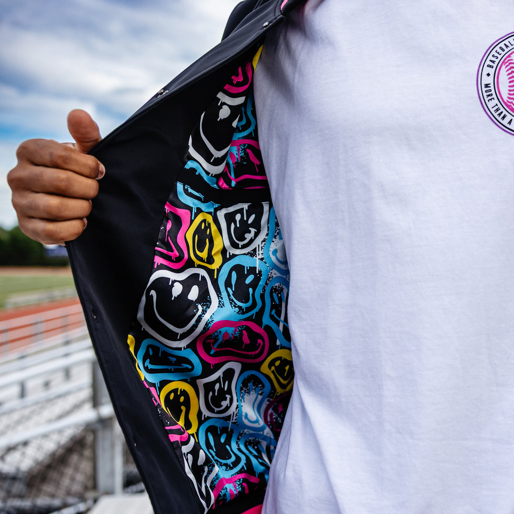 Person holding a jacket with colorful smiley face pattern outdoors