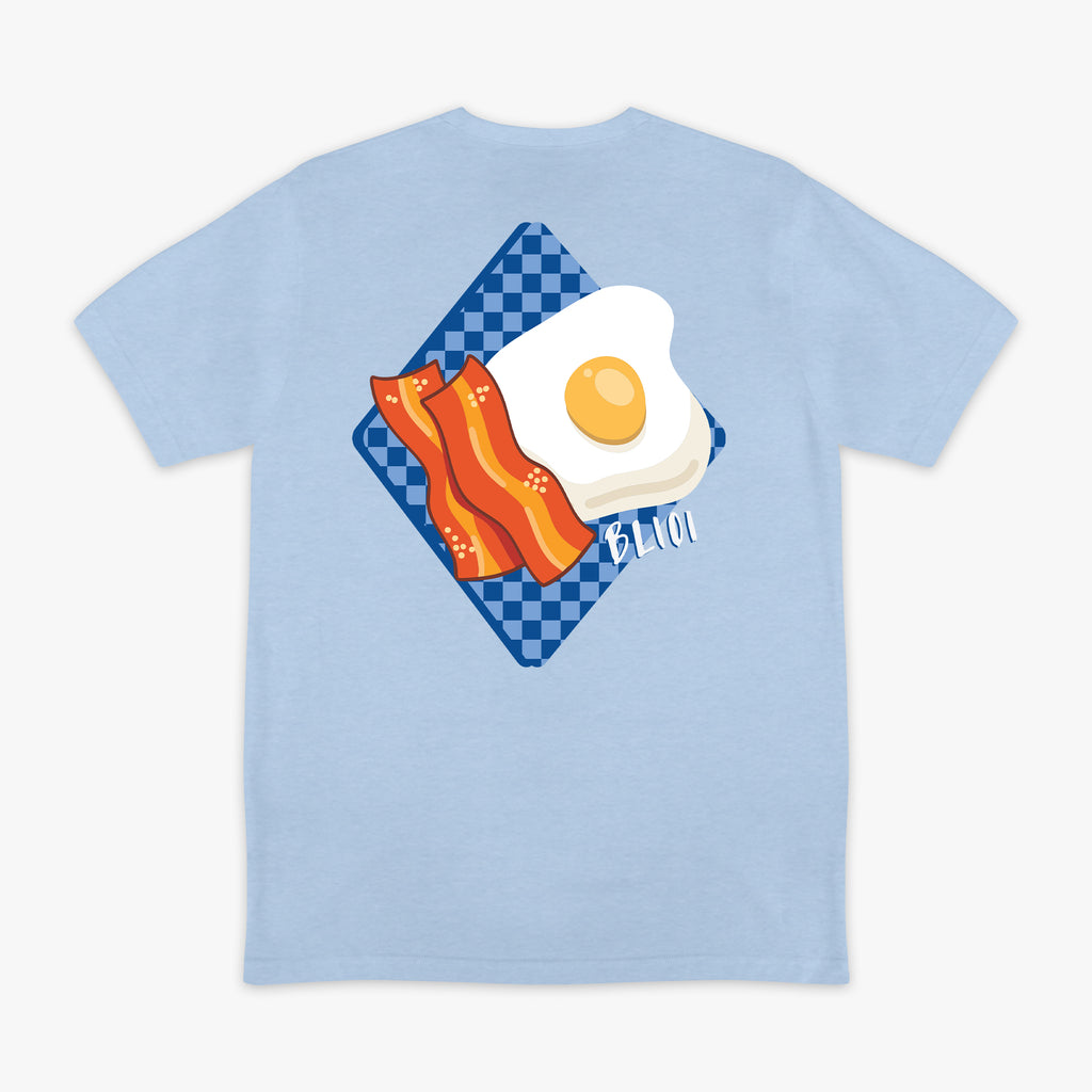 Light blue t-shirt with a graphic of an egg and bacon on a checkered plate with BL101 logo. 