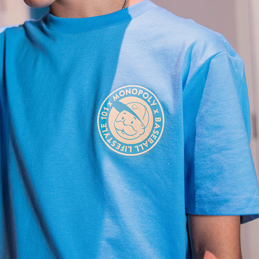 Adult model wearing graphic tee with “BL101 x Monopoly” design