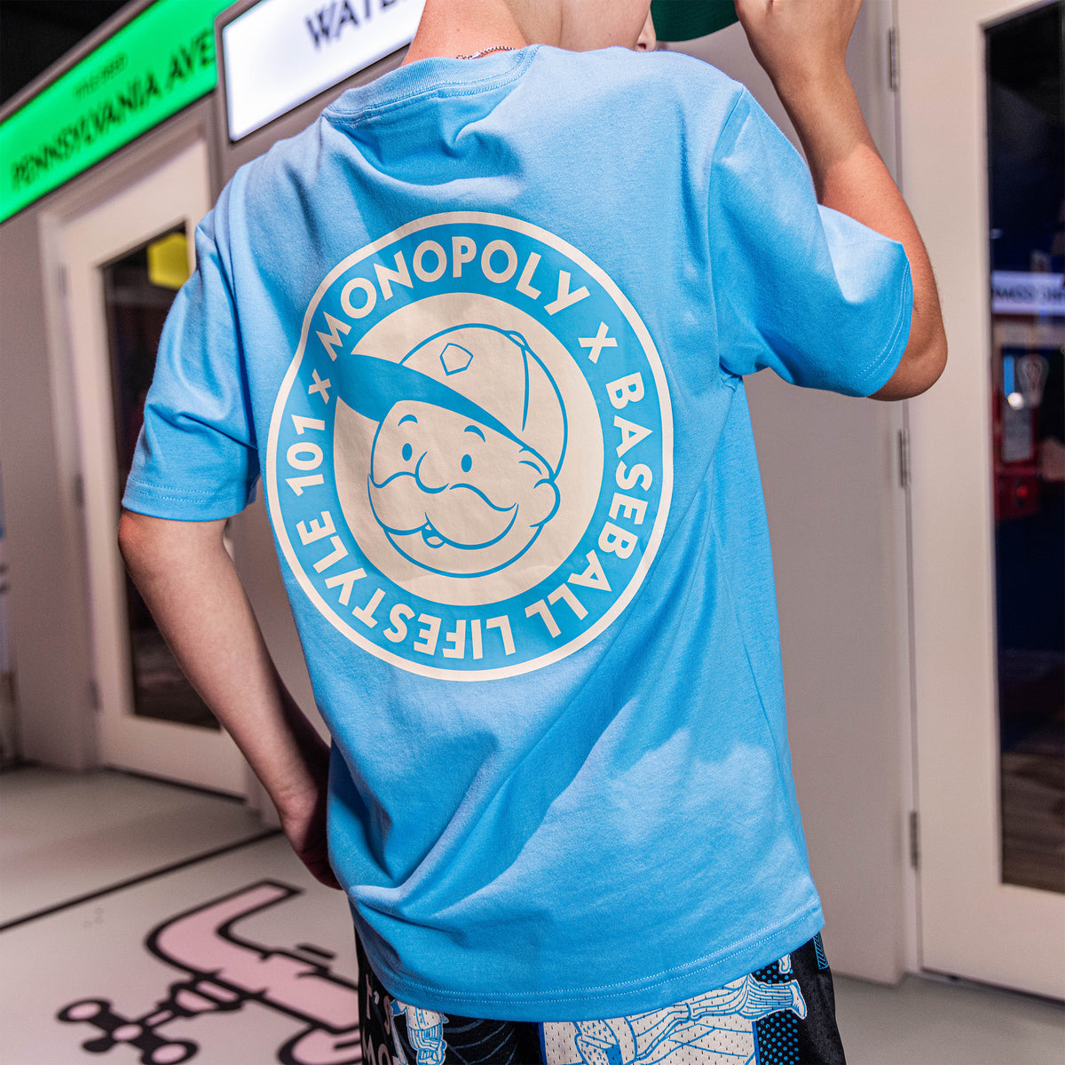 Adult model wearing graphic tee with “BL101 x Monopoly” design