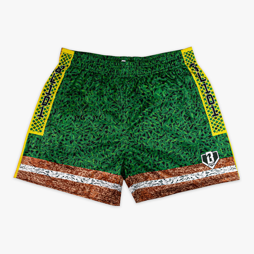 Front flat lay of BL101 baseball field mesh shorts featuring a grass-texture body, dirt and chalk line hem, yellow diamond-pattern side panels with BL101 text, and BL101 logo on a white background.