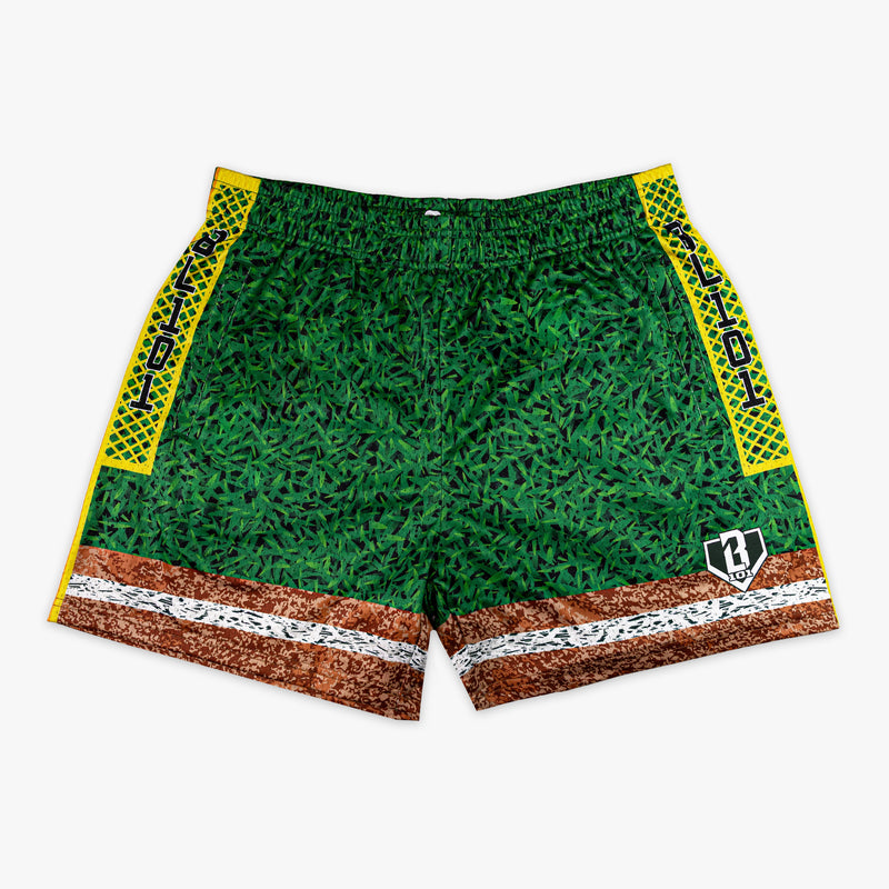 Front flat lay of BL101 baseball field mesh shorts featuring a grass-texture body, dirt and chalk line hem, yellow diamond-pattern side panels with BL101 text, and BL101 logo on a white background.