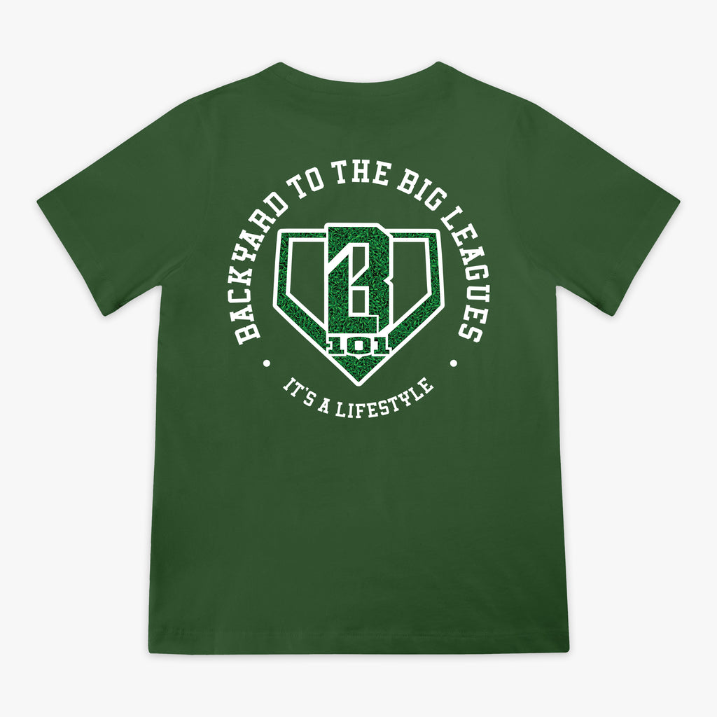Back flat lay of the BL101 Backyard to the Big Leagues forest green tee, featuring a circular "It's a Lifestyle" graphic with a grass-textured BL101 logo on a white background
