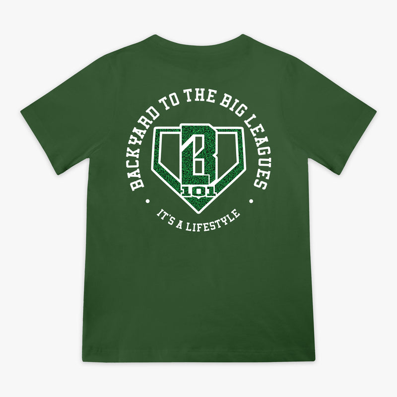 Back flat lay of the BL101 Backyard to the Big Leagues forest green tee, featuring a circular "It's a Lifestyle" graphic with a grass-textured BL101 logo on a white background