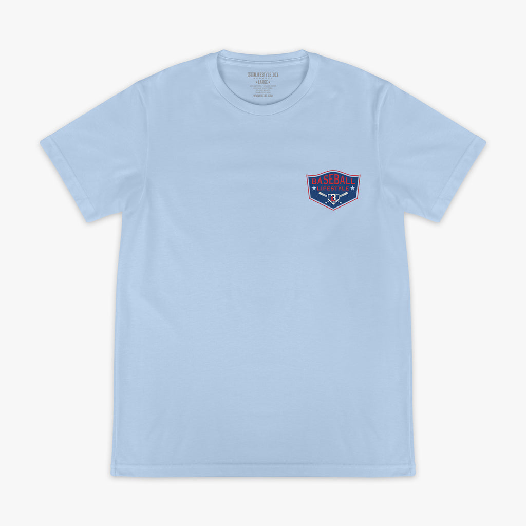 Front flat lay of the BL101 Baseball League Champions light blue tee, showing the Baseball Lifestyle shield chest logo on a white background.