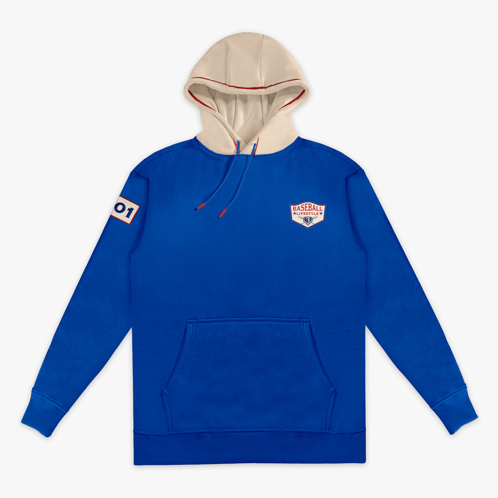 Royal blue hoodie with a cream hood, showing the Baseball Lifestyle shield chest logo, sleeve patch, and red drawstring on a white background.