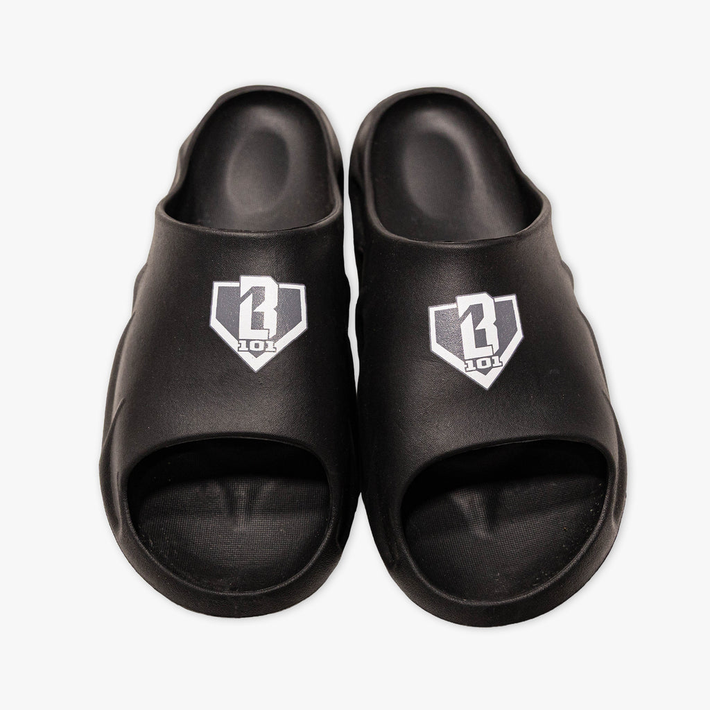 Top-down view of BL101 black slides with a gray and white home plate logo on a white background.