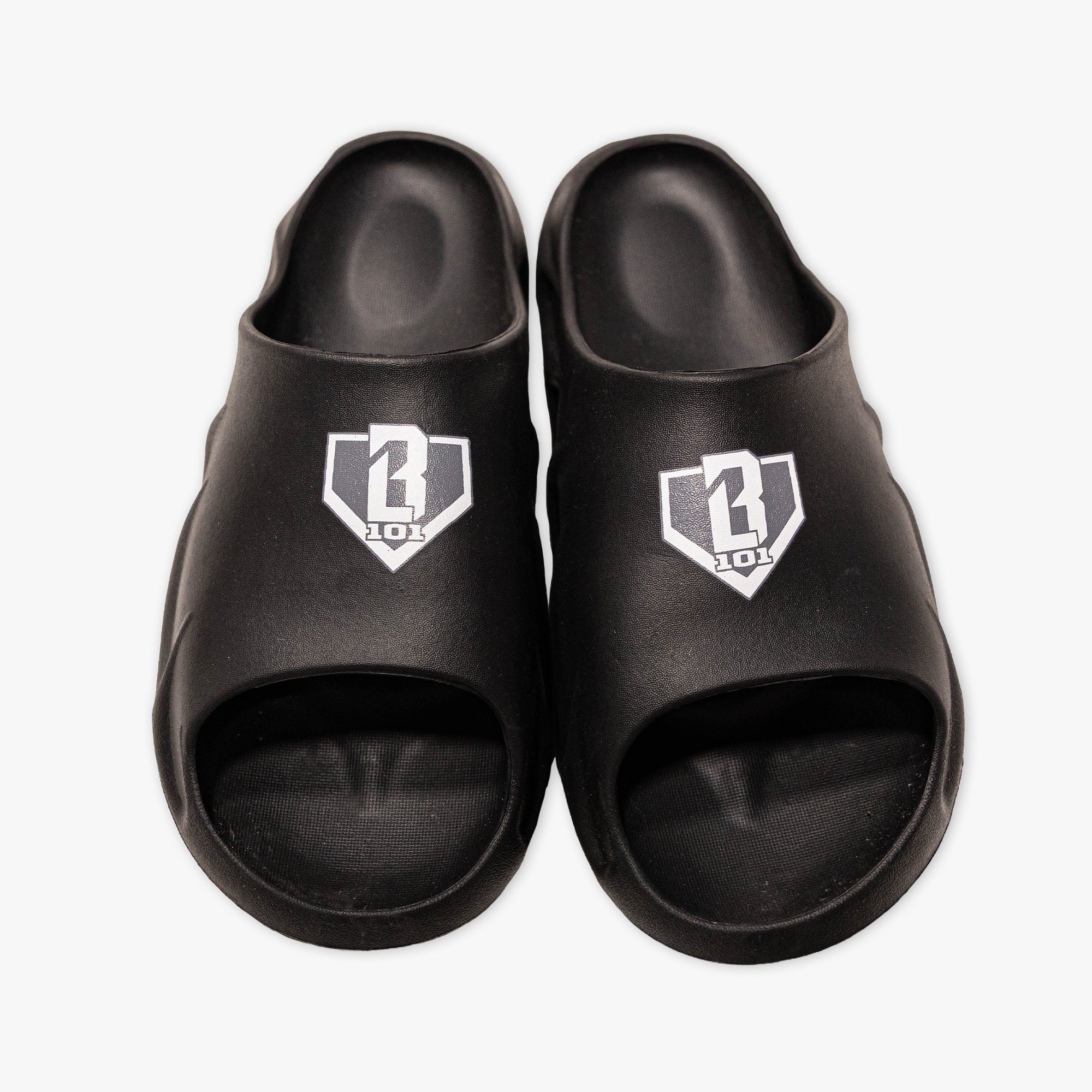 Top-down view of BL101 black slides with a gray and white home plate logo on a white background.